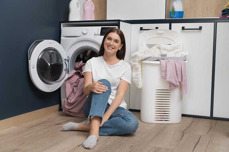 woman sitting washing machine with basket full clothes 1